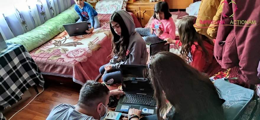 Voluntarii asociației instalând laptopuri donate copiilor pentru școala online